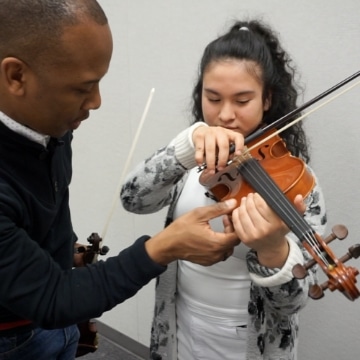 Dr Quinton Morris with violin student in gray flower cardigan