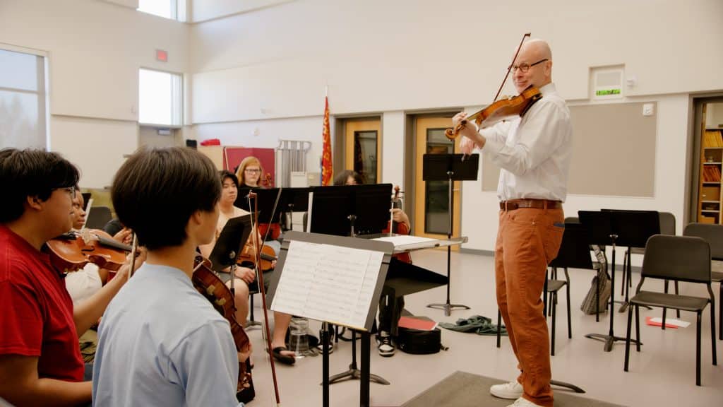 Dr. Svend Ronning, the concertmaster of Symphony Tacoma and Professor of Violin at Pacific Lutheran University mentors violinists during a string sectional.