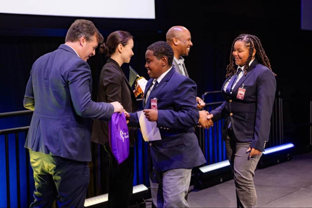 Staff at Key To Change Studio in Renton - from left to right: Mr. Robert Simonds, Dr. Natasha Kubit, and Dr. Quinton Morris - shake hands with students from Cristo Rey Jesuit High School in Seattle.