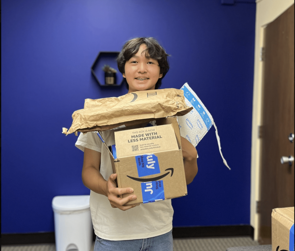 Violin student Thomas Luu holds deliveries of items donated by supporters through Key to Change’s Amazon Wish List.